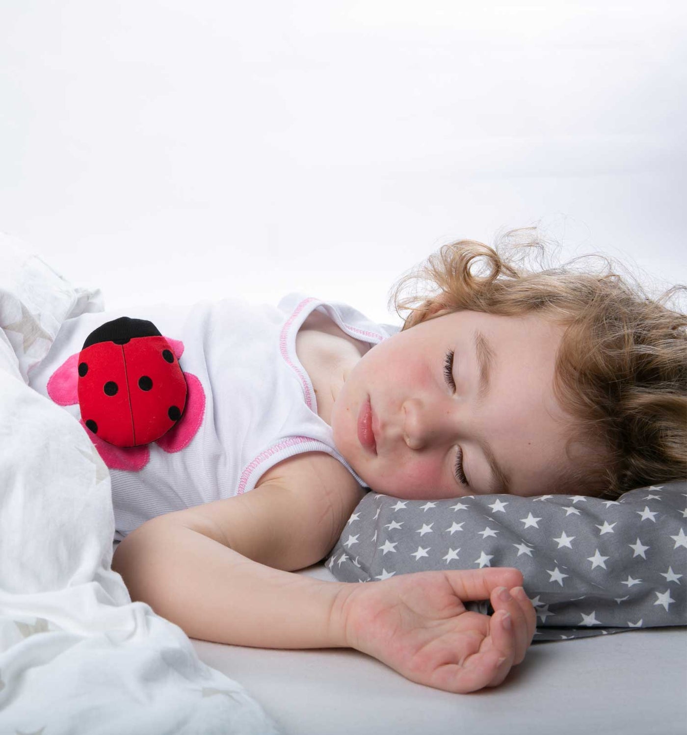 smartes Marienkäfer Wearable wacht auf Unterhemd während Kind schläft. Erfasst Temperatur, Atmung und Bewegungsverhalten